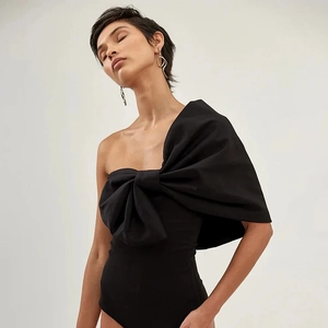 Détail d'un maillot de bain noir à une épaule orné d'un grand nœud papillon élégant