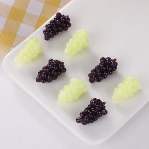 Miniature grape stress toys in purple and green on a white plate, close-up view