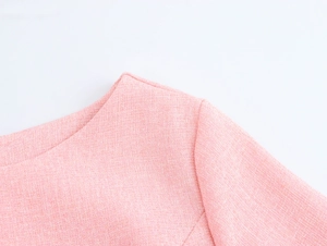 Detail of pink tweed dress showing the round neckline and shoulder texture