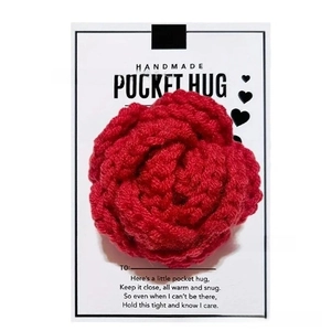 Macro detail of a red crocheted heart with a handmade pocket hug greeting card gift