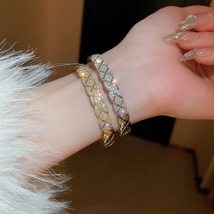 Close-up of gold and silver quilted lattice bracelets with micro-paved zircons on a wrist