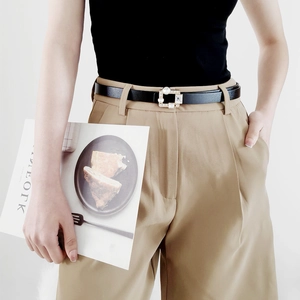 Detail of slim black PU leather belt with rhinestone buckle on khaki trousers