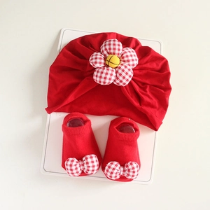 Detail view of red infant turban hat with checkered flower and matching bow socks