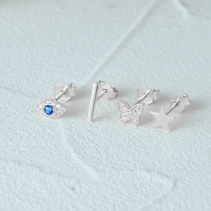 Detailed macro view of S925 sterling silver butterfly, star, and blue eye stud earring set