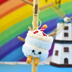 Cute plush cake keychain with strawberry and candle details on a bright rainbow background