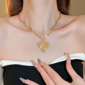 Close-up of a model wearing a gold geometric triangle pendant with vintage relief patterns