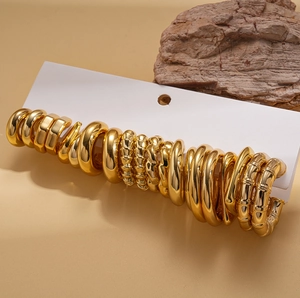 Detail view of 20-piece gold geometric twisted earrings set on white card with wood decor