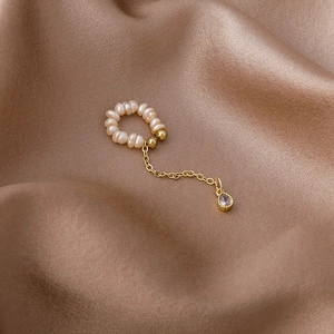 Detail of freshwater pearl cuff with gold chain and teardrop zircon on brown satin