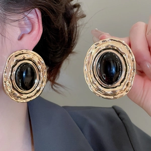 Dettaglio di orecchini ovali vintage con bordi dorati e cabochon nero centrale