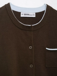 Detail shot of a brown knit cardigan featuring contrast blue piping and ribbed texture