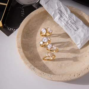Golden titanium steel rings with zircon stones displayed on a luxury stone tray