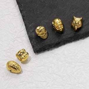 Detailed view of golden stainless steel skull, wolf, and buddha beads for jewelry making