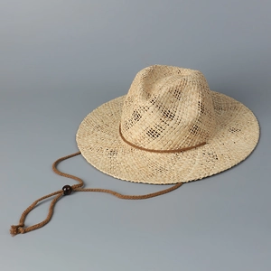 Détail de la texture d'un chapeau de paille avec cordon réglable et perle en bois brun