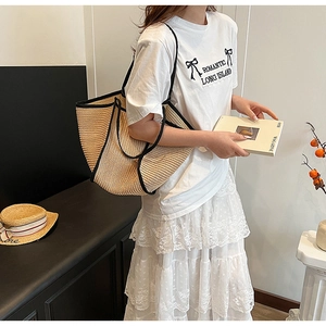 Straw woven tote bag featuring khaki body and black trim styled with a casual summer outfit