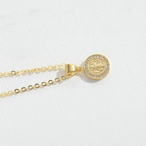 Detail of gold-plated pendant with religious figure relief and micro-set zircon accents
