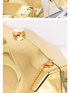 Detail of glossy gold acrylic clutch box bag showing polished metallic finish and chain strap