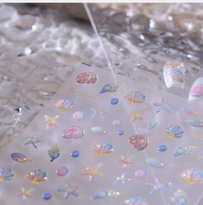 Makroansicht von Muschel- und Seestern-Nagelstickern mit Goldrand und 3D-Ozeanmustern