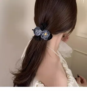 Detail of grey satin flower hair claw with black lace and gold metal core on hair