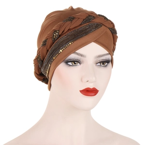 Detail of a brown sequined turban hat featuring a thick braided cross design with gold threads