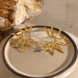 Luxury gold sunburst earrings with irregular molten texture on ceramic surface