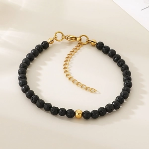 Macro detail of black volcanic lava beads with gold accents and heart charm chain