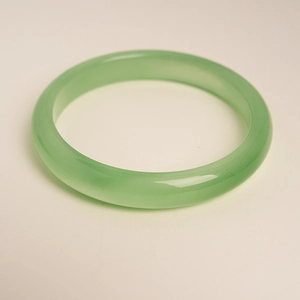 Detailed view of a translucent pale green cat-eye stone bangle with smooth finish