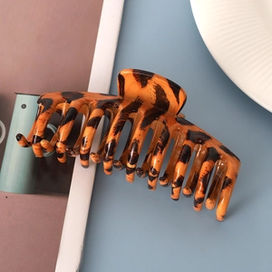 Detail of a large leopard print hair claw clip on a flat surface next to a magazine