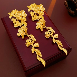 Détail de boucles d'oreilles fleuries en or mat avec de longs pompons élégants
