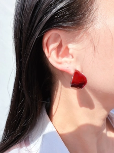 Close-up of a model wearing dark red enamel leaf earrings with silver metal edges