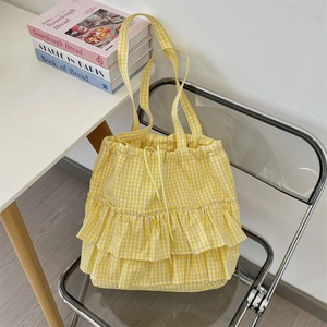 Detail of yellow plaid canvas tote with lace ruffle trim and drawstring on clear chair