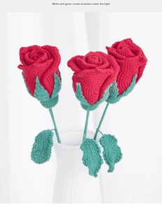 Detail of three handmade crochet red roses with green leaves in a white ceramic vase