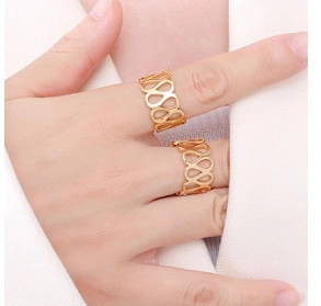 Detailed close-up of golden hollowed-out infinity rings worn on fingers with a minimalist design