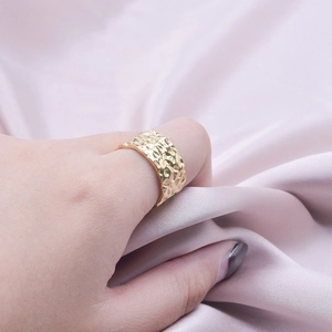 Adjustable gold-plated textured hammer pattern stainless steel ring on silk background