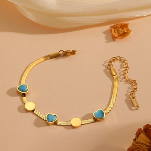 Gros plan d'un bracelet serpent en acier doré avec des breloques cœurs turquoise
