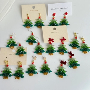 Close-up of handmade beaded Christmas tree earrings with colorful crystals on white background