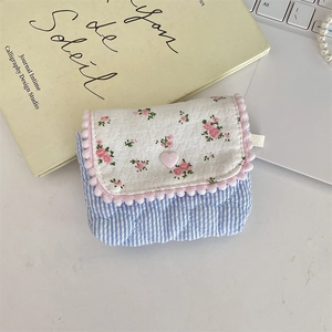 Top view of a floral quilted storage pouch with pom-pom trim and heart button detail