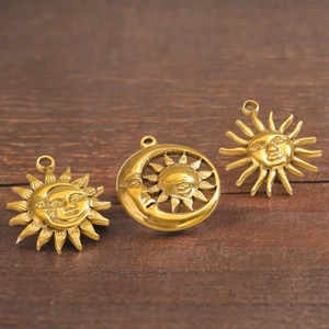 Detailed view of three vintage gold sun and moon pendants on a dark wood background