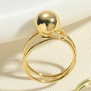 Macro shot of minimalist gold double ring with a large polished spherical metal bead detail