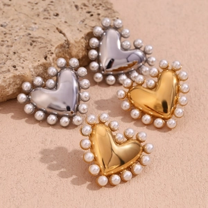 Macro view of heart-shaped gold and silver earrings with pearl trim on a textured stone