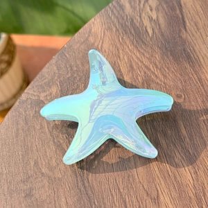 Detail shot of a laser iridescent starfish hair claw clip on a rustic wooden texture