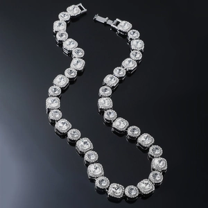 Macro detail of silver hip hop necklace with square and round crystals on black surface
