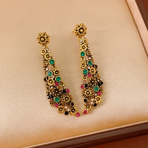 Détail de boucles d'oreilles vintage aux motifs floraux et strass sur un coussin beige