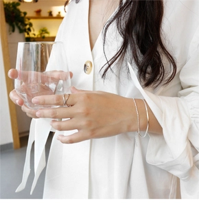 Detail of elegant S925 sterling silver layered bracelet and rings on model's hand