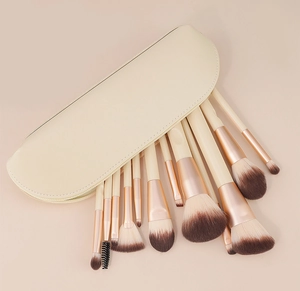 Vista dettagliata di 12 pennelli trucco con ghiere in oro rosa e una custodia beige