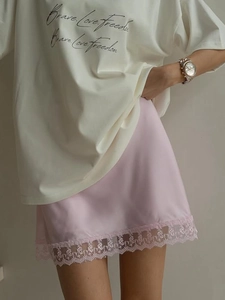 Detailed view of pale pink satin skirt hem with delicate lace trim and soft texture