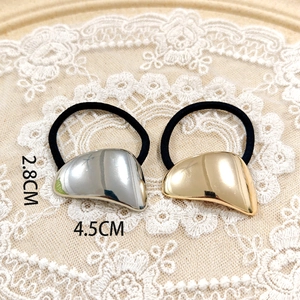 Close-up of gold and silver irregular geometric metal hair ties on lace background