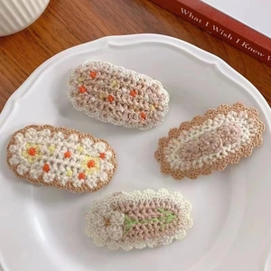 Detail of four handmade crochet flower hair clips on a decorative white porcelain plate