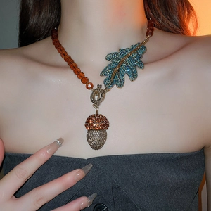 Détail du collier de perles ambrées avec pendentifs feuille et gland porté par un mannequin
