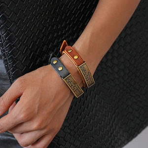 Detailed macro view of black and brown leather bracelets with vintage engraved metal plates