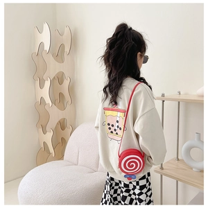 Rear view of a child wearing a red lollipop shaped crossbody bag on a beige sweatshirt